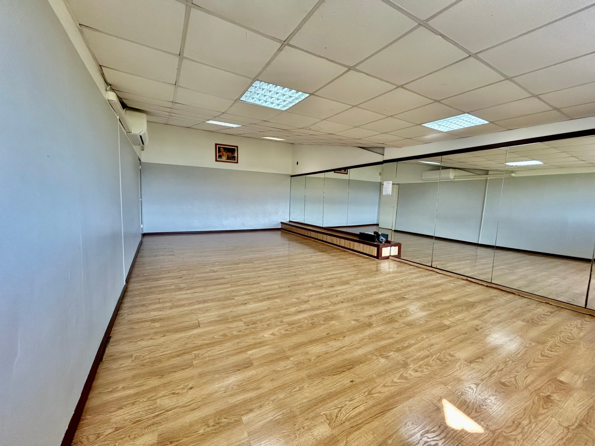 Salle 2, parquet clair et mur de miroirs avec estrade